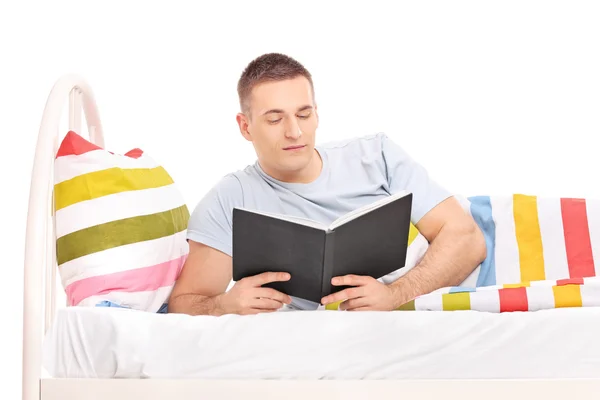 Mann liest Buch im Bett — Stockfoto