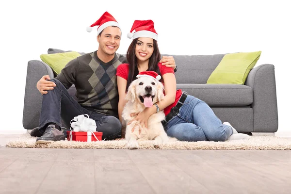 Paar in Santa hoeden met hond — Stockfoto