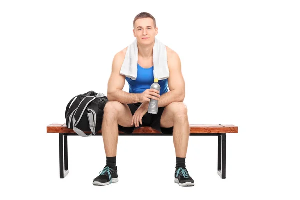 Athlete on bench holding water — Stock Photo, Image