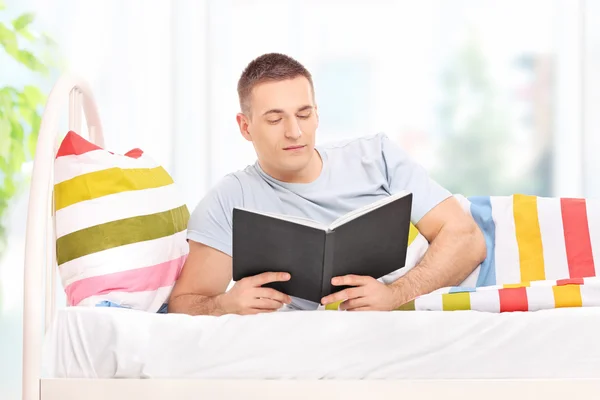 Hombre leyendo un libro en la cama — Foto de Stock