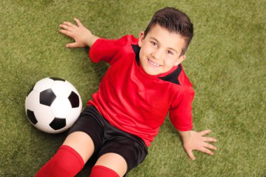 Genç futbolcu sahada oturan