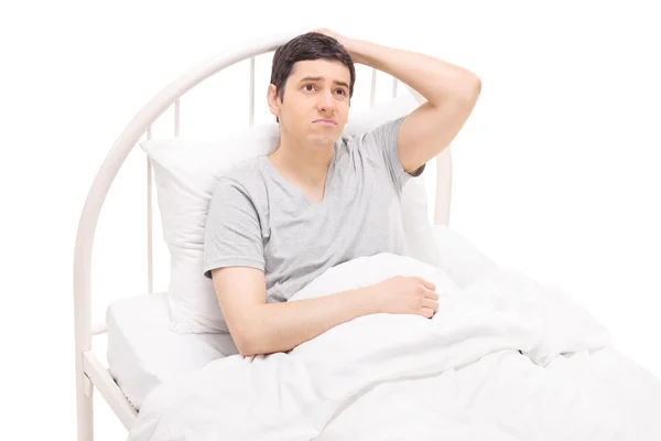 Confused guy lying in bed — Stock Photo, Image