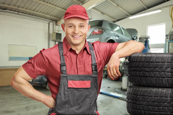 Mécanicien appuyé sur les pneus dans le garage — Photo