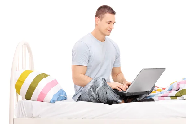 Mannen i pyjamas arbetar på bärbar dator — Stockfoto