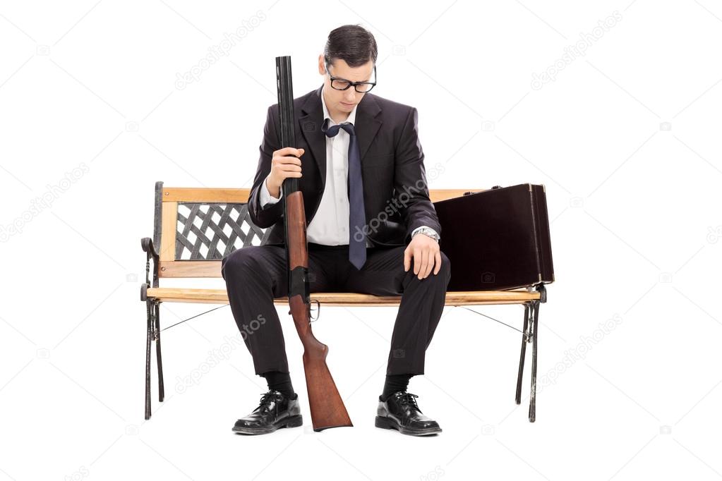 Depressed businessman holding a shotgun rifle