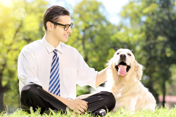 草の上に座っている犬を持ったビジネスマン — ストック写真