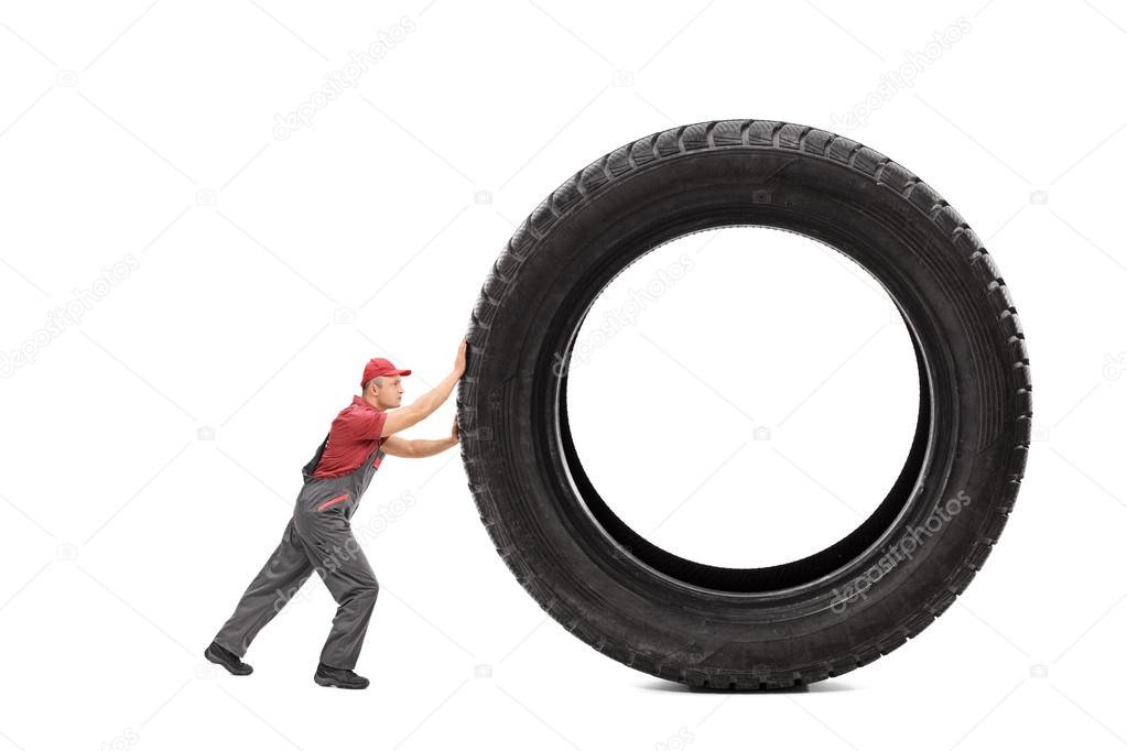 Mechanic pushing a giant black tire
