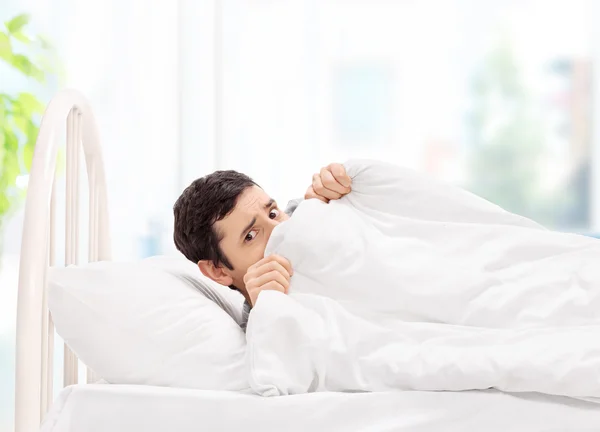 Tipo en la cama escondido debajo de la manta — Foto de Stock