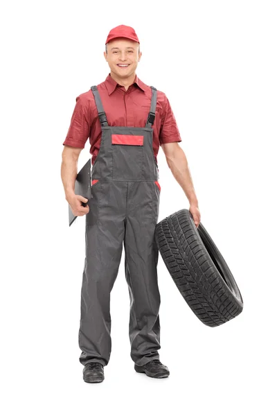 Mechanic holding a tire and clipboard — Stock Photo, Image