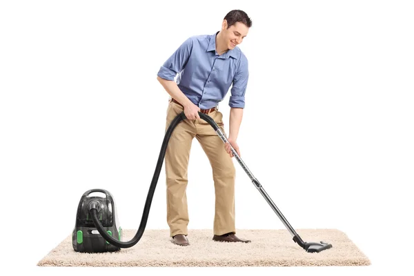 Чоловік чистить килим за допомогою пилососа — стокове фото