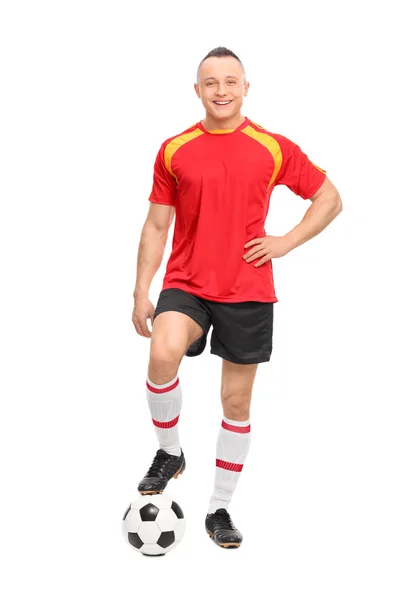 Bir top üzerinde duran futbolcu — Stok fotoğraf