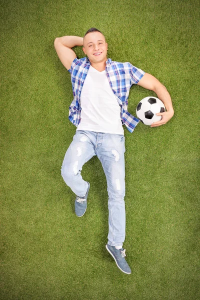 Homme couché sur le terrain avec le football — Photo