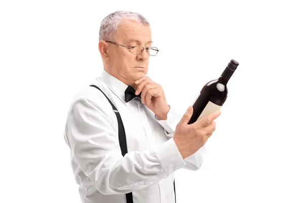 Старший читает этикетку на бутылке вина — стоковое фото