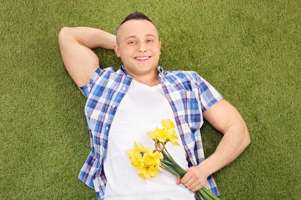 Homme sur herbe tenant des fleurs — Photo