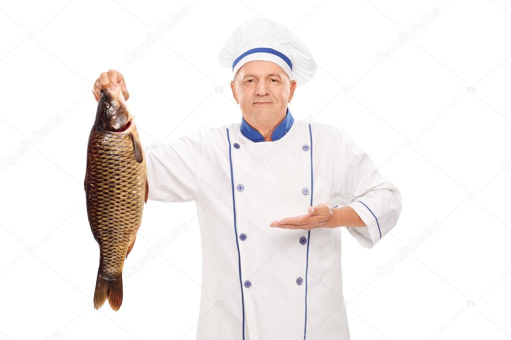 Mature chef holding freshwater fish