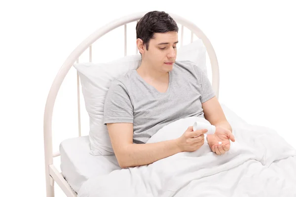 Hombre en una cama tomando medicamentos — Foto de Stock