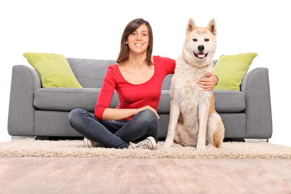 Girl with her dog seated by a couch — Stock Photo, Image