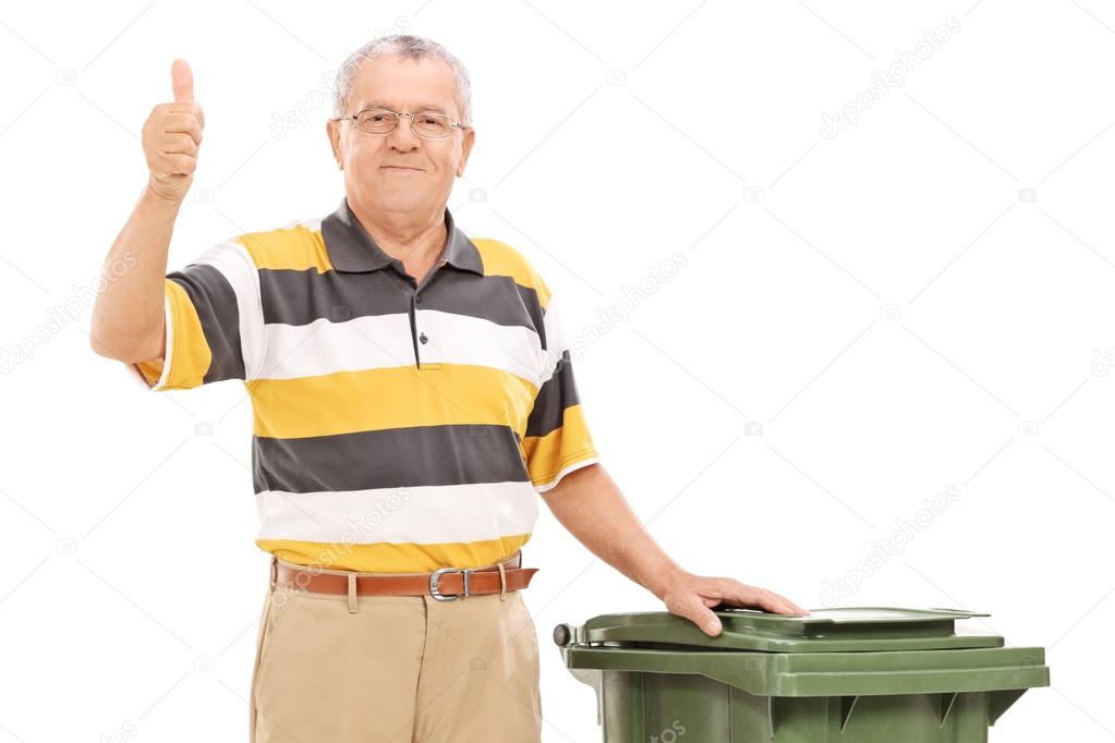 Satisfied senior standing by a trash can