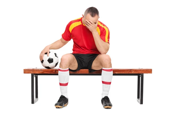 Worried football player sitting on a bench — Stock Photo, Image