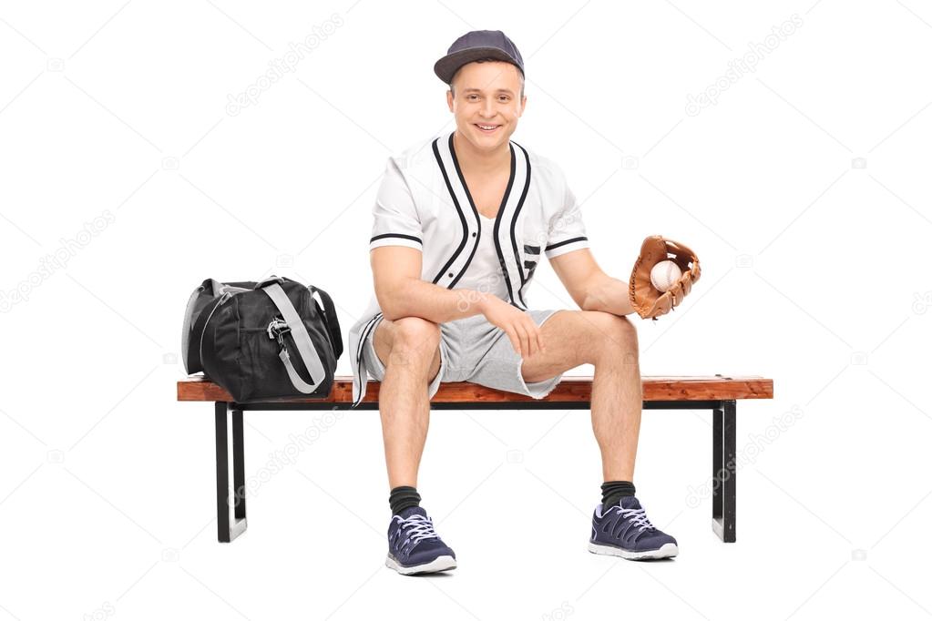 Sportsman holding a baseball on bench