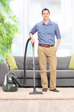 Genç adam bir elektrikli süpürge ile poz 