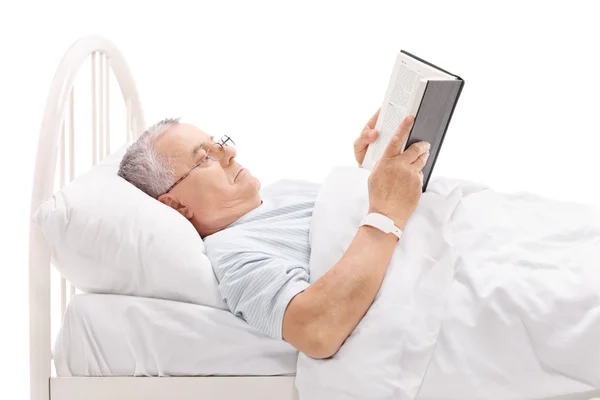 Paciente maduro leyendo libro en la cama —  Fotos de Stock