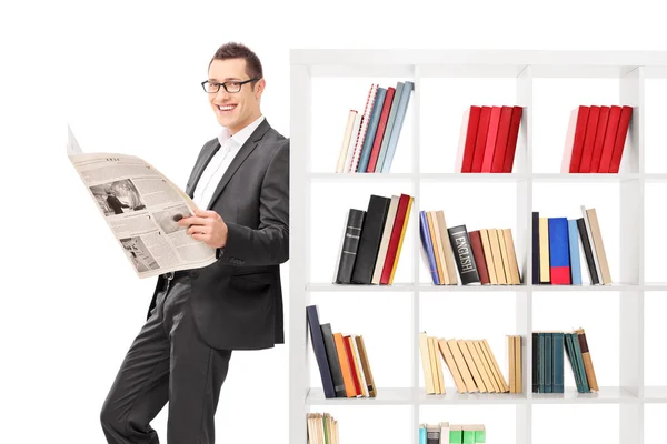Zakenman houden een papier en leunend op de boekenplank — Stockfoto