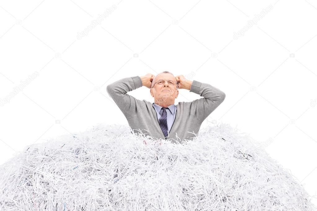 Senior man stuck in a pile of paper