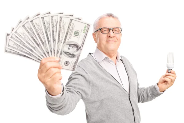 Hombre sosteniendo bombilla y dinero —  Fotos de Stock