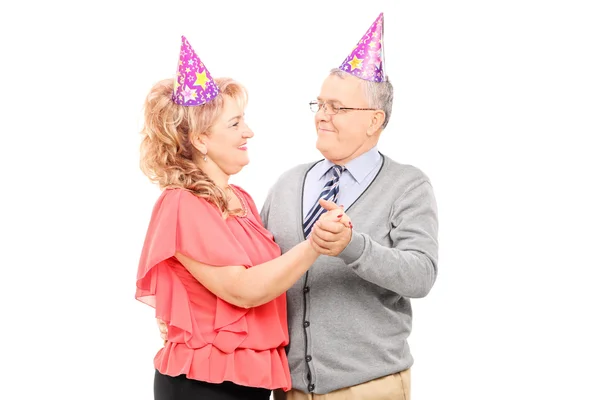 Зрелая пара в шляпах для вечеринок танцует — стоковое фото