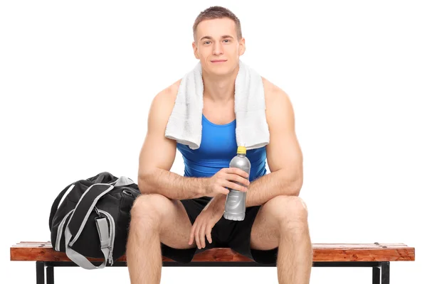 Muscular athlete sitting on a wooden bench — Stock Photo, Image