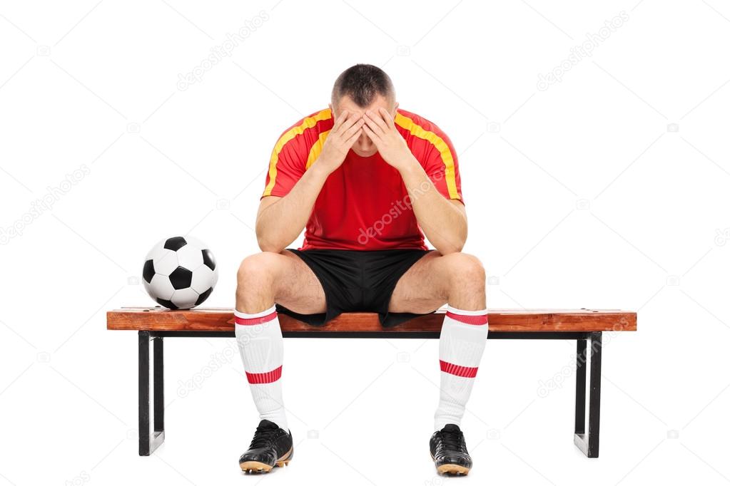 Worried football player sitting on a bench