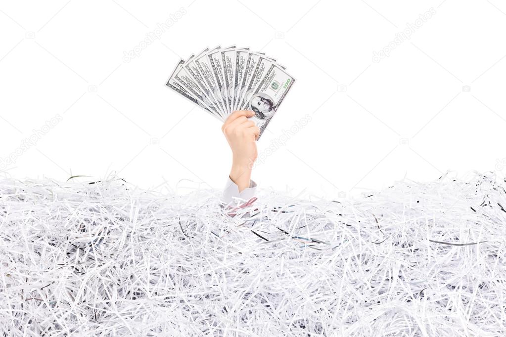 Hand holding money in a pile of paper