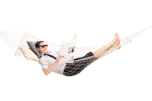 Relaxed man reading newspaper in a hammock — Stock Photo, Image