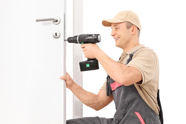 Fabbro avvitando una vite su serratura di una porta — Foto Stock