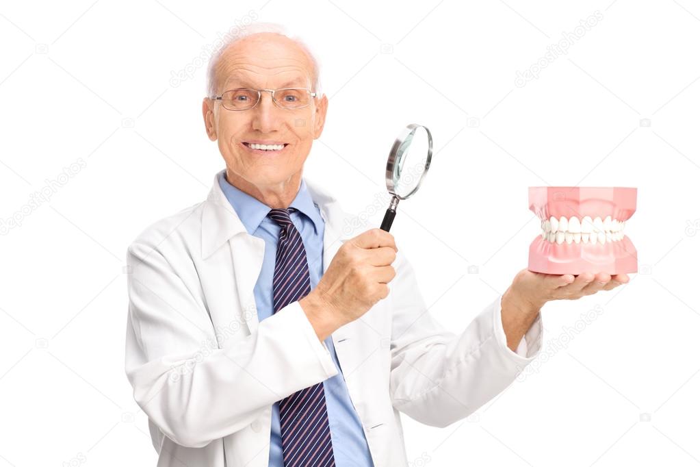 Dentist holding denture and a magnifying glass 