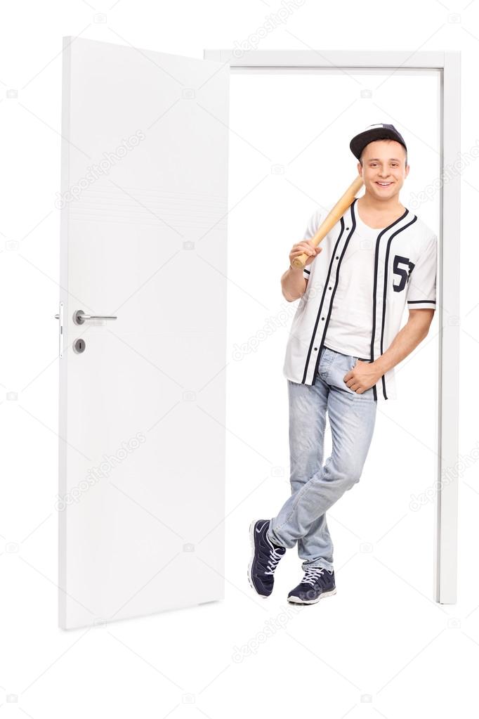 Young baseball player leaning on a door 