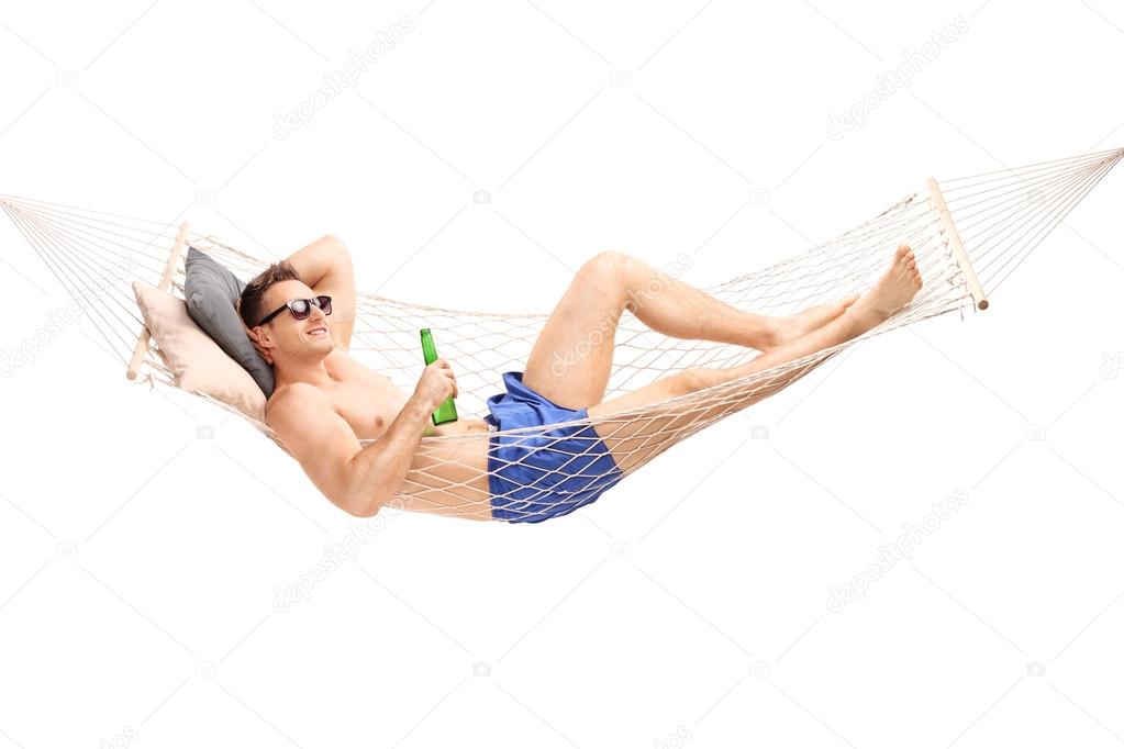 Handsome man lying in a hammock with a beer
