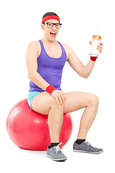 Nerdy guy sitting on fitness ball — Stock Photo, Image