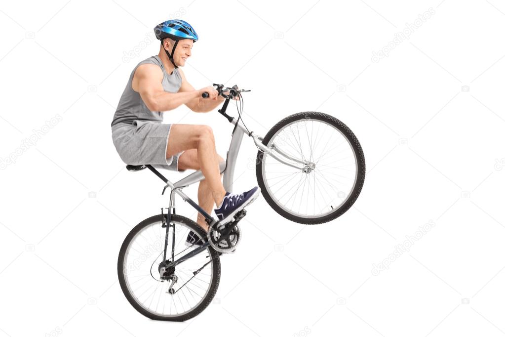 Joyful young biker doing a wheelie