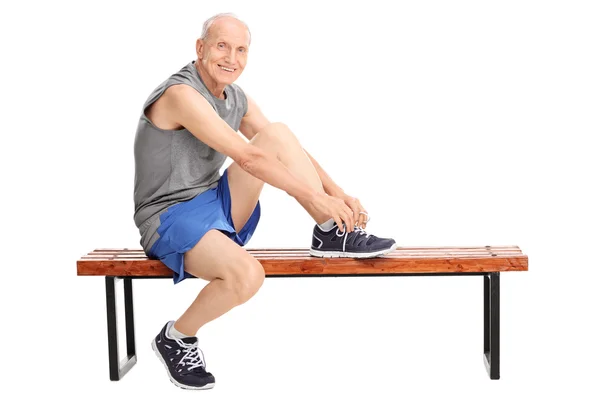 Старший чоловік у спортивному одязі зав'язує шнурки — стокове фото