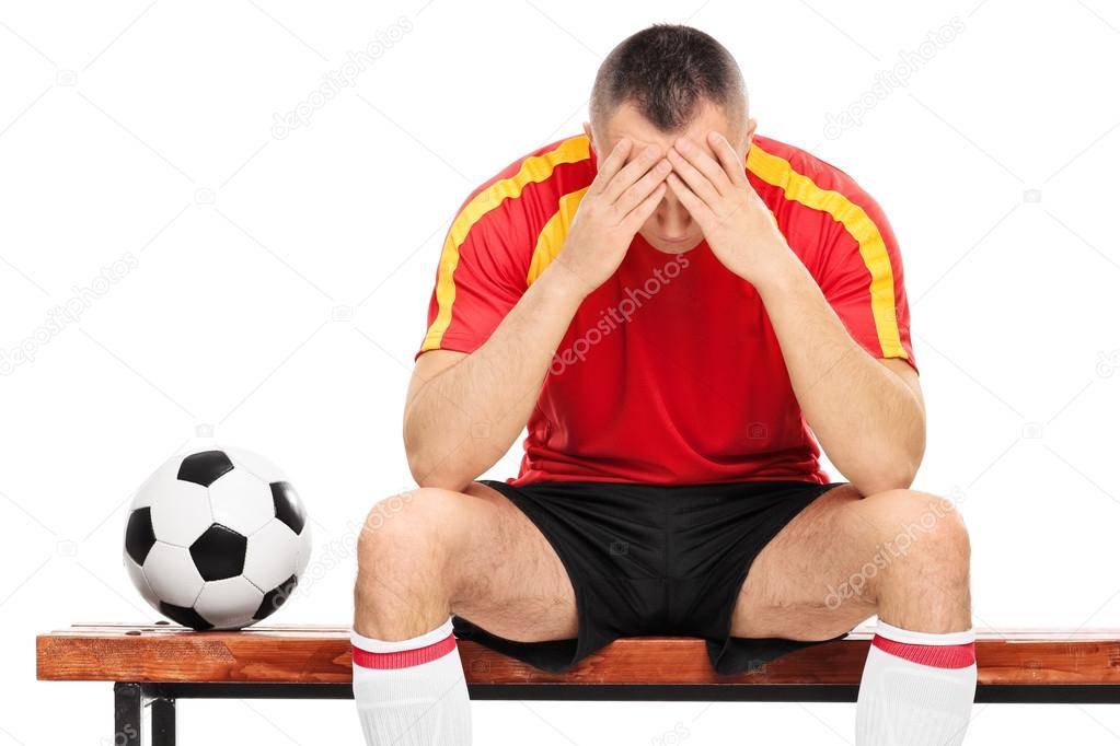 Worried football player sitting on bench