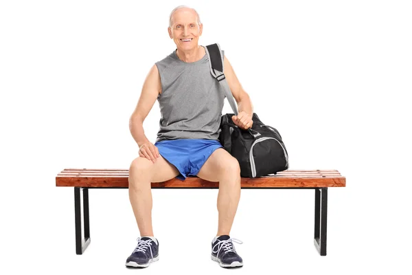 Пенсионер, сидящий на деревянной скамейке — стоковое фото