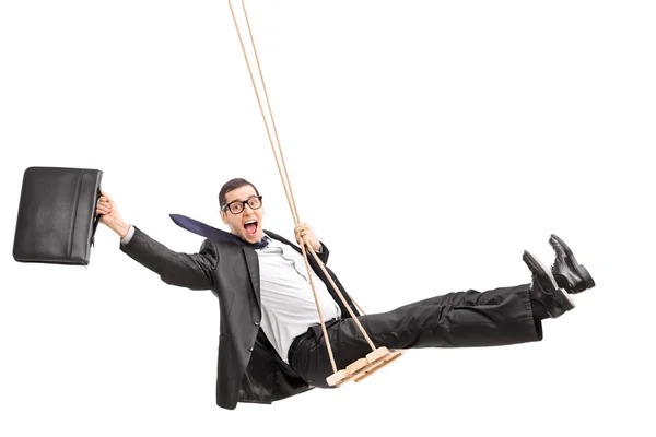 Delighted young businessman swinging on a swing — Stock Photo, Image