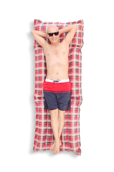 Senior man lying on a swimming mattress — Stock Photo, Image