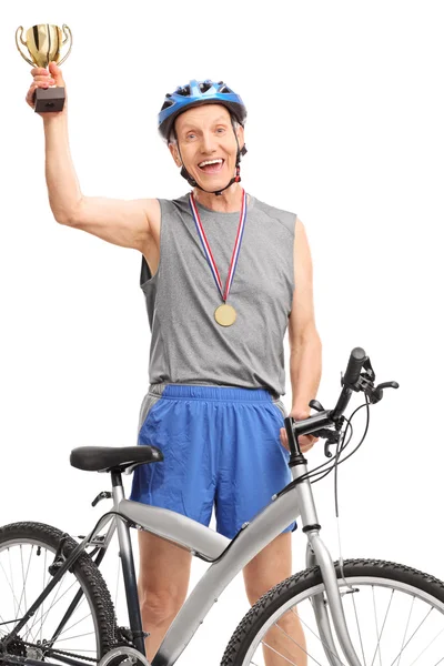 Senior cyclist holding a golden trophy — Stock Photo, Image