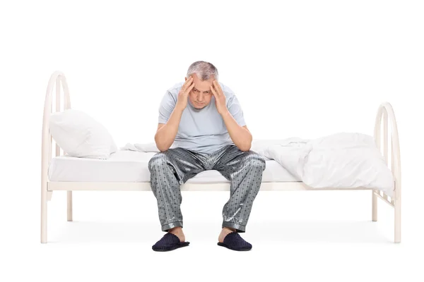 Frustrated senior man sitting on a bed — Stock Photo, Image