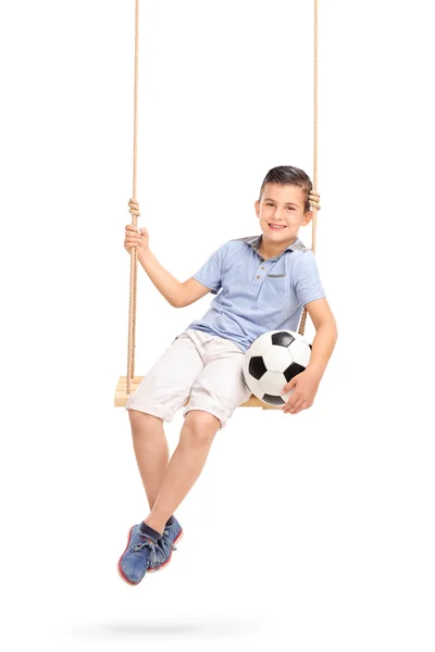 Niño sosteniendo el fútbol sentado en un columpio — Foto de Stock