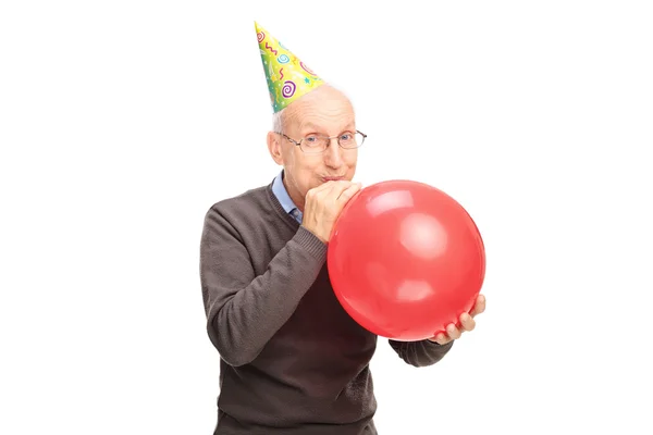 Wesoły człowiek starszy wysadzenie balon — Zdjęcie stockowe