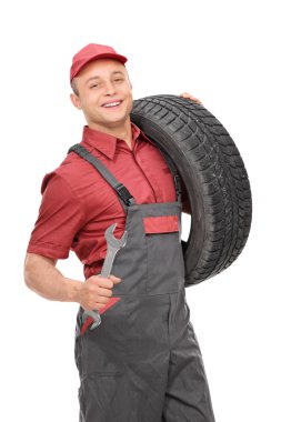 bir lastik ve bir İngiliz anahtarı tutan genç makinist